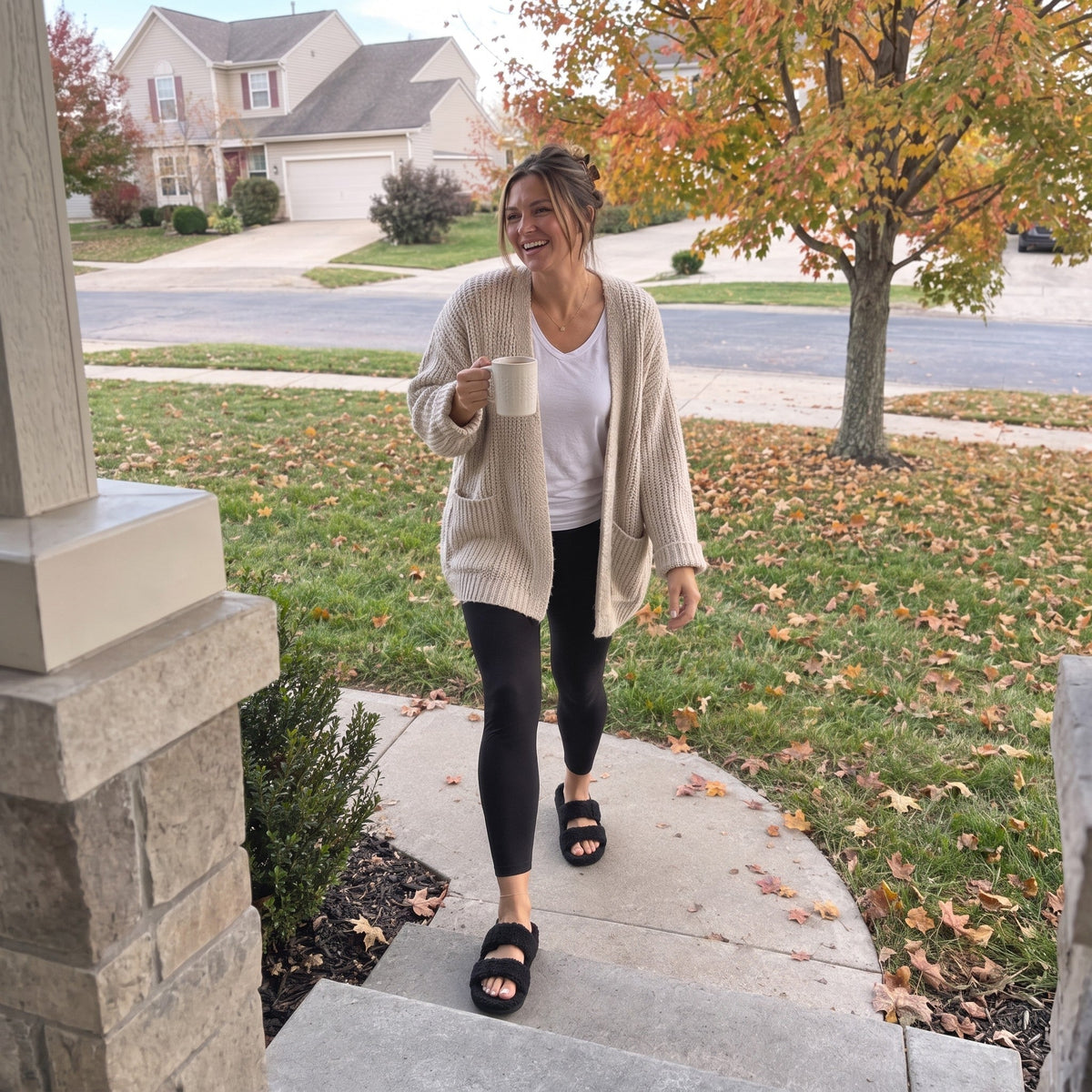 Woman walking up her front path in Fuzzy slides in Matt Black, autumn morning