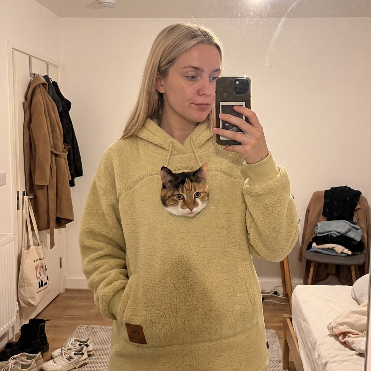 Mirror selfie in the Meowdie cat pocket hoodie in Yellow, cat in the zip pouch